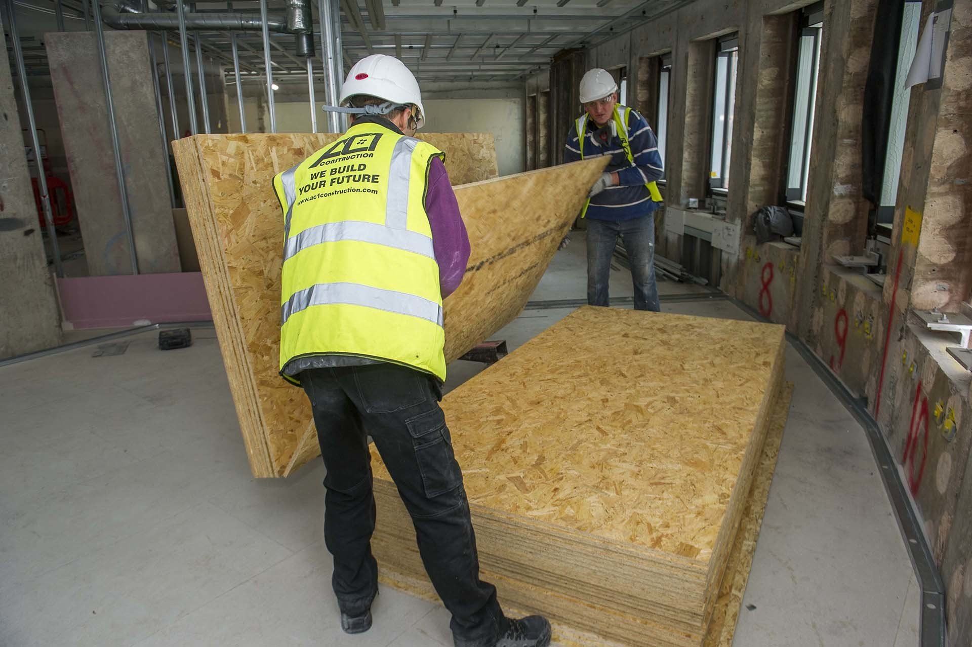 AC1 operative carrying timber boards on site